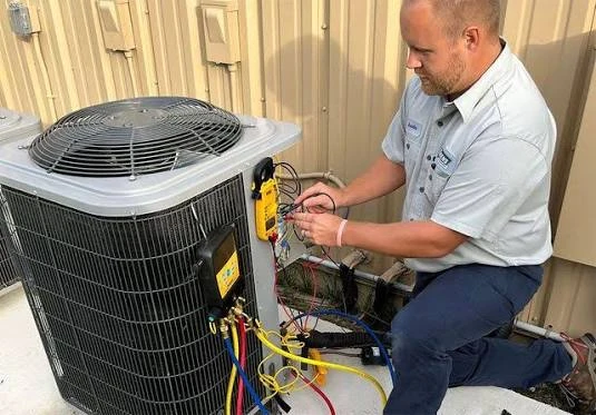 Illustrative HVAC technician using a meter and service gauges at an outdoor condenser