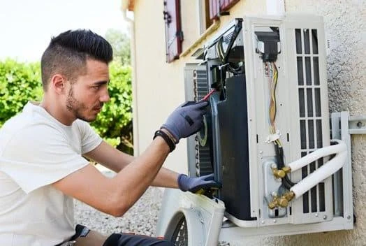 Illustrative technician examining an opened wall-mounted outdoor air conditioning unit